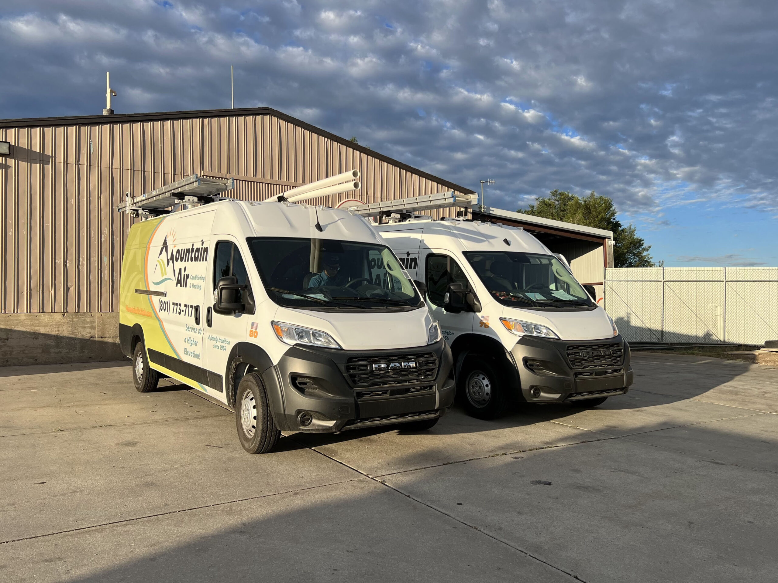 Two Mountain Air service trucks parked side-by-side in front of a warehouse.