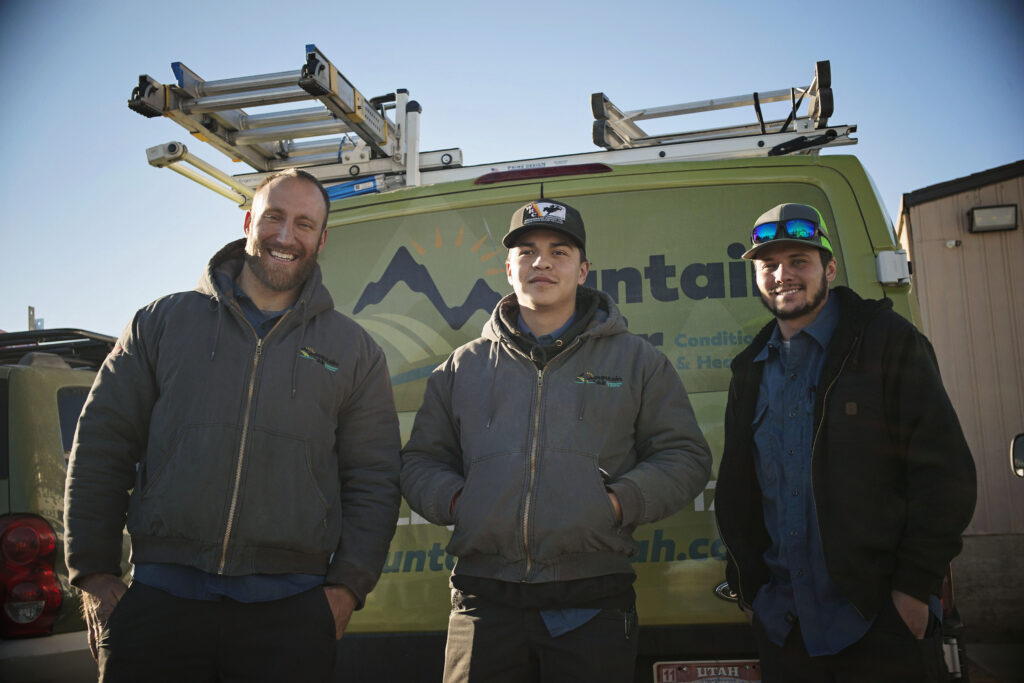 Three Mountain Air HVAC technicians standing in front of a service van.
